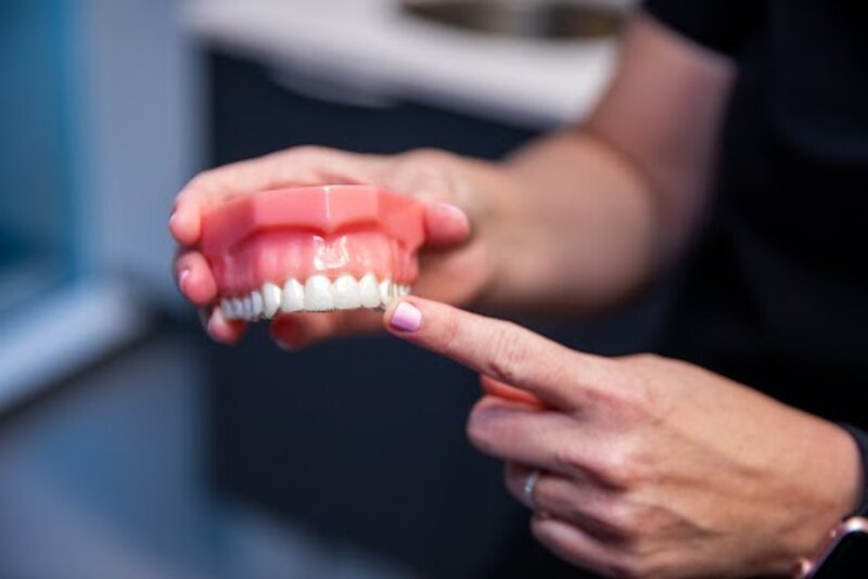 dentist pointing to a pair of model top dentures