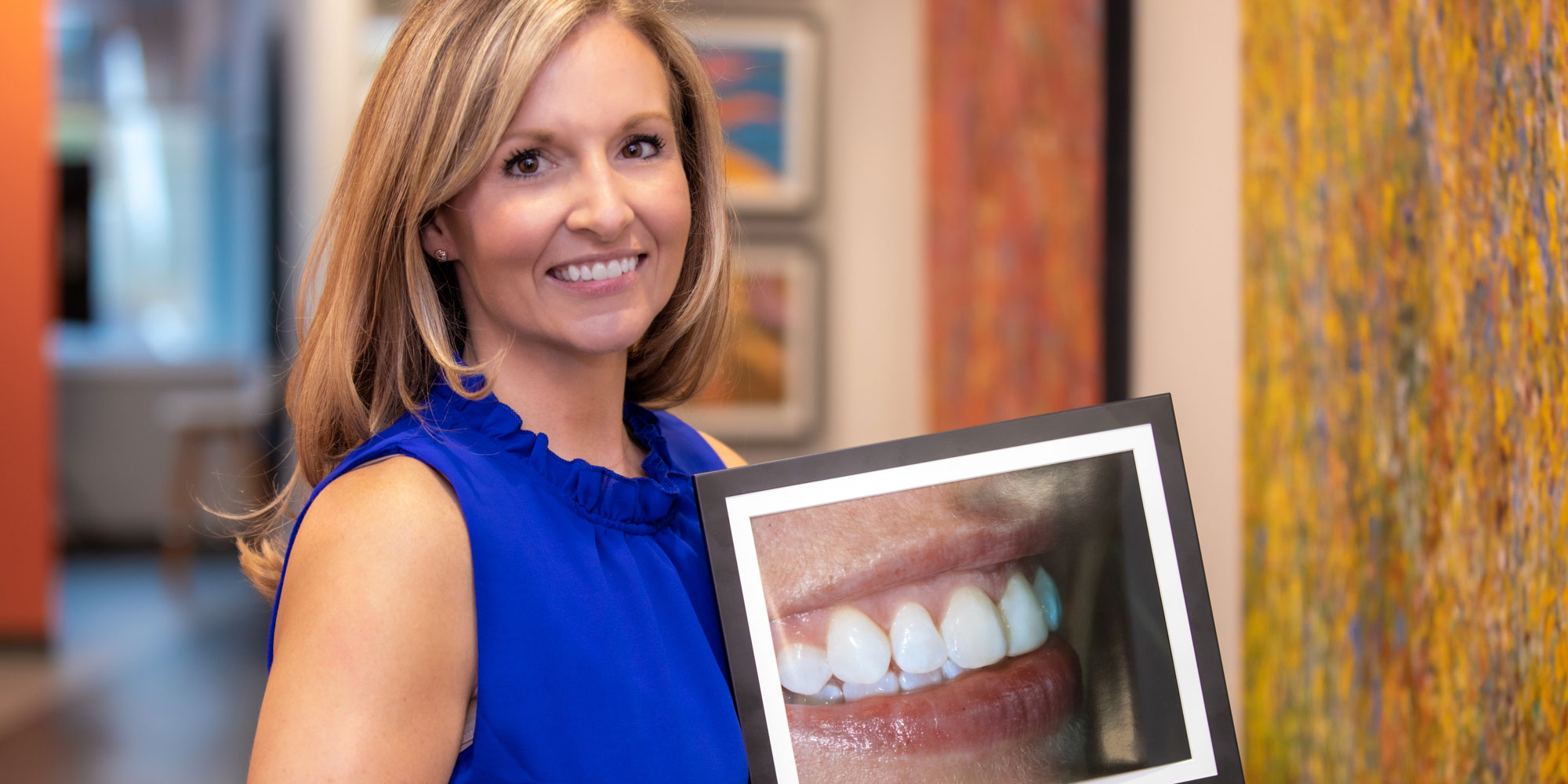 lindsey a patient at bluegrass dentistry holding up a photo of her new smile